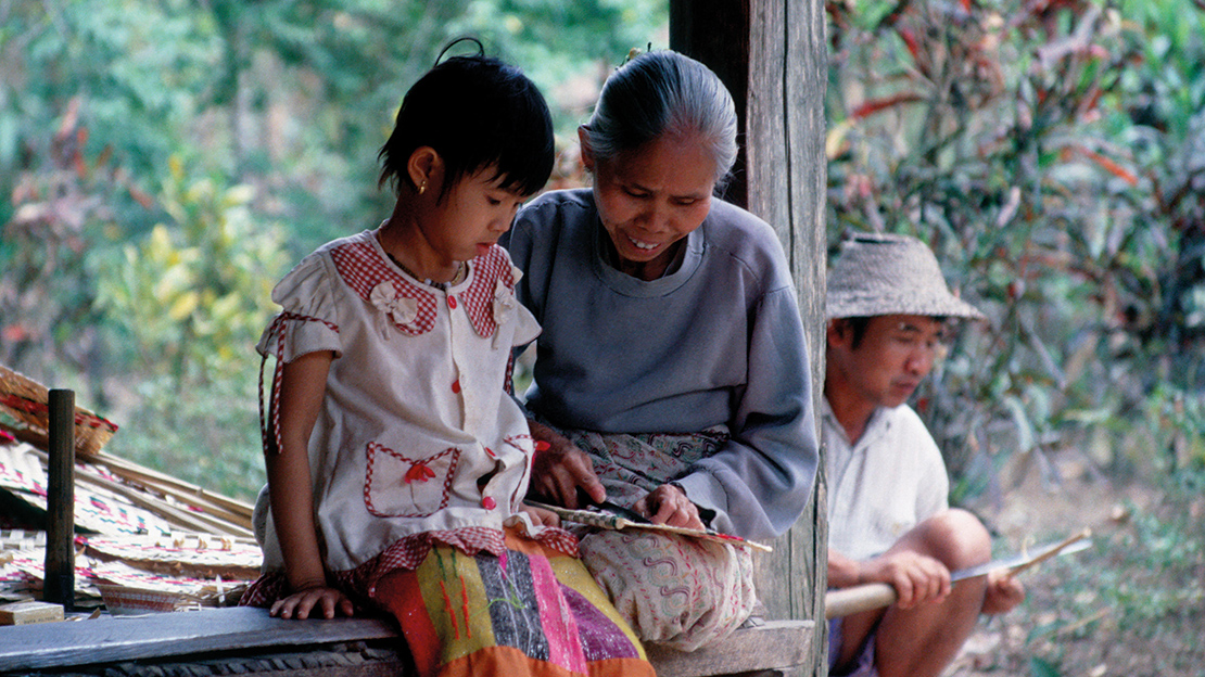 An indigenous Shan woman teaches her granddaughter how to make a bamboo fan near Hsipaw, Shan State, Myanmar. Credit: Ray Waddington.