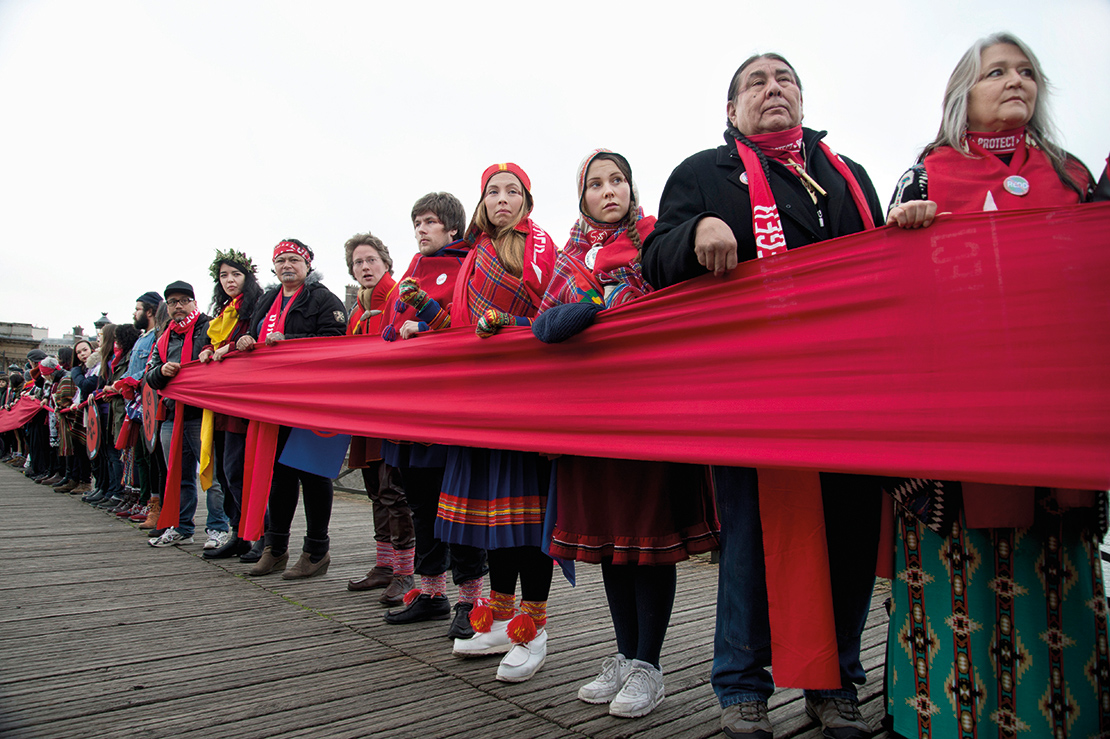 Indigenous activists holding a 'Red Line' on the Pont des Arts during the COP 21 UN Climate Conference in Paris, France. IPLCs are participating actively in policy forums and global climate change initiatives. Credit: Jenny Matthews.